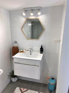 La salle de bains est pourvue d'un lavabo blanc et d'un miroir. dans l'établissement The Cosy Bungalow, à Portarlington