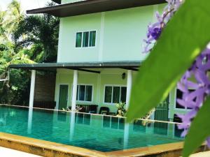 a villa with a swimming pool in front of a house at Subsavet Village in Baan Tai