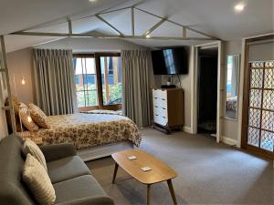 a bedroom with a bed and a couch and a tv at The Cosy Bungalow in Portarlington