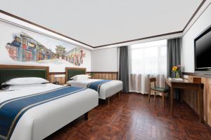 ein Hotelzimmer mit 2 Betten und einem Flachbild-TV in der Unterkunft 时光漫步酒店太原理工大学公元时代城店 in Taiyuan