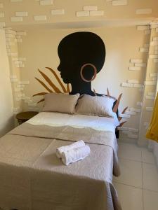 a bed with a towel on it with a painting on the wall at Aconchego de Itapuã in Salvador