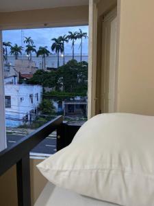 a bedroom with a bed and a window with palm trees at Hostel dos Poetas in São Luís