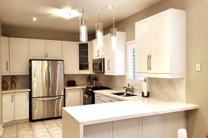 uma cozinha com armários brancos e um frigorífico de aço inoxidável em Modern & Spacious 2 Bedrooms+2 Bathrooms Bungalow in Oakville em Oakville