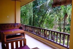 a balcony with a wooden bench and a large window at Jati 3 Bungalows and Spa in Ubud