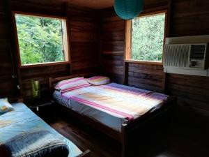 a bedroom with two beds in a wooden cabin at La Casa de Colores in Garuhapé