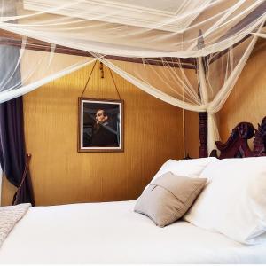 a bedroom with a canopy bed with white sheets at South Court Inn in Luray