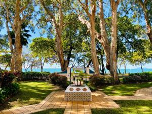 een bankje in een park met bomen en gras bij BeachView Apartments at Villa Paradiso in Palm Cove