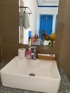 La salle de bains est pourvue d'un lavabo blanc et d'un miroir. dans l'établissement Ha Na Đức Linh, 