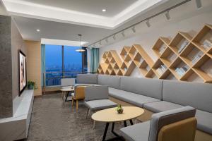 a waiting room with a couch and tables and chairs at Joysuites Nantong in Nantong