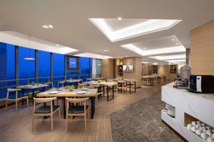 un restaurante con mesas y sillas de madera y paredes azules en Joysuites Nantong, en Nantong