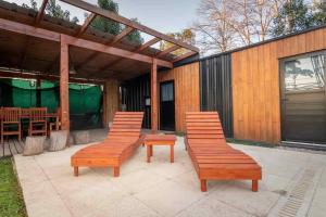 dos bancos sentados en un patio frente a un edificio en Cabaña del Mangrullo. Con piscina y Mirador. en Villa Leloir