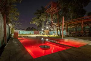 Cabaña del Mangrullo. Con piscina y Mirador. في Villa Leloir: حمام سباحة مع إضاءة حمراء في موقف للسيارات في الليل
