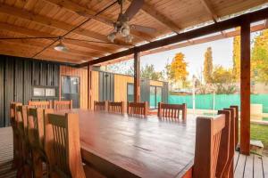 una gran mesa de madera y sillas en una terraza en Cabaña del Mangrullo. Con piscina y Mirador. en Villa Leloir