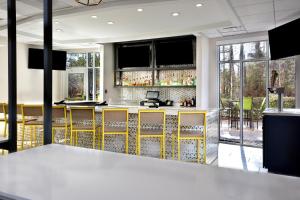 a bar with yellow accents in a room with windows at Holiday Inn Raleigh Durham Airport, an IHG Hotel in Morrisville