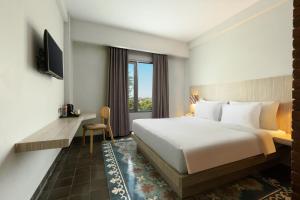 une chambre d'hôtel avec un lit et une fenêtre dans l'établissement Burza Hotel Yogyakarta, à Yogyakarta