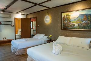Cette chambre comprend deux lits et un tableau mural. dans l'établissement Rimsuan Garden Home, à Chiang Mai