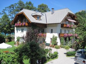 a large white house with flowers in the yard at Landhaus Leitner am Wolfgangsee in Sankt Gilgen