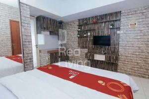 ein Schlafzimmer mit einem TV in einer Ziegelwand in der Unterkunft RedLiving Apartemen Green Lake View Ciputat - Pelangi Rooms 3 Tower E in Tangerang