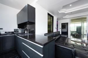 a kitchen with a black counter top and a living room at PATONG TOWER FAMILY APARTMENT by PTA in Patong Beach