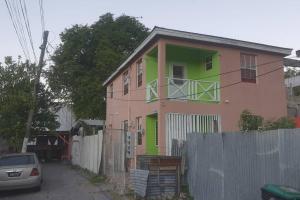 a pink and green house with a fence at El Palacio Apartments in Bridgetown