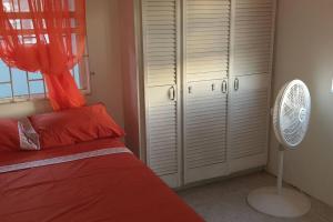 a bedroom with a bed with red pillows and a fan at El Palacio Apartments in Bridgetown