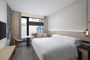 a bedroom with a large white bed and a table at AC Hotel by Marriott Suzhou China in Suzhou