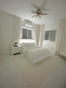 een witte slaapkamer met een bed en een plafondventilator bij Moss Manor in Marsh Harbour
