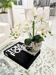 une table en verre avec un vase de fleurs sur un livre dans l'établissement Moss Manor, à Marsh Harbour