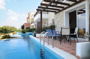 a patio with a table and chairs next to a swimming pool at Chrispy Waterpark Resort - All inclusive in Kolymvari