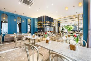 ein Restaurant mit blauen Wänden, Tischen und Stühlen in der Unterkunft Jovia Hotel in Ho-Chi-Minh-Stadt