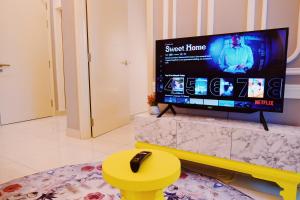 uma sala de estar com uma televisão de ecrã plano e um banco amarelo em Arte Mont Kiara Homestay em Kuala Lumpur