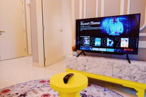 a living room with a flat screen tv and a yellow stool at Arte Mont Kiara Homestay in Kuala Lumpur