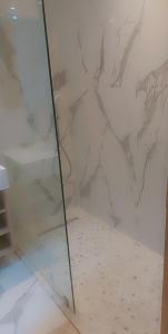 La salle de bains est pourvue d'une douche en verre et d'un mur en marbre. dans l'établissement Luxury Studio Princess, à Casablanca
