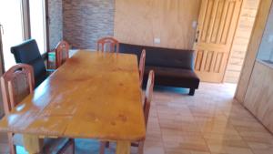 een houten tafel en stoelen in een kamer met een bank bij Cabaña pullay in Cobquecura