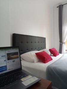 un ordenador portátil sentado en un escritorio junto a 2 camas en Guest House d Valeri, en Labuan Bajo