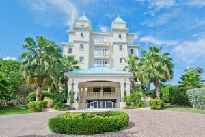 a large white building with palm trees in front of it at Sea Breeze, Grand Cayman in West Bay