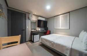 a bedroom with a bed and a desk in it at Alps Motel in Incheon