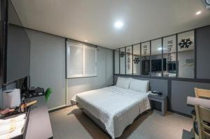 a bedroom with a bed and a desk and a window at Alps Motel in Incheon