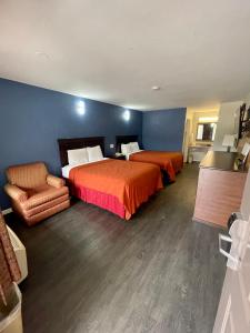 a hotel room with two beds and a chair at Key West Inn - Roanoke in Roanoke
