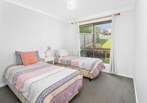 two beds in a room with a window at Beachside Retreat in Gerringong