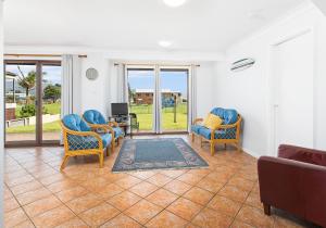 a living room with chairs and a tv and sliding glass doors at Beachside Retreat in Gerringong