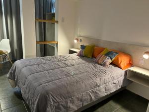 1 dormitorio con 1 cama grande y almohadas coloridas en Monoambiente céntrico en Mendoza en Mendoza