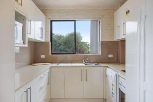 a white kitchen with a sink and a window at Apollo Unit 20 Ground Floor in Narooma