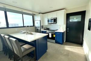 a kitchen with a sink and a counter with chairs at Luxury 2BR Condo Rosarito (E) in Rosarito