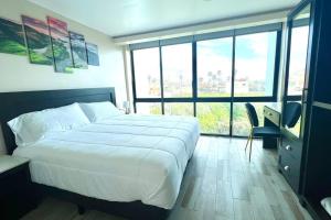 a bedroom with a white bed and a desk and windows at Luxury 2BR Condo Rosarito (E) in Rosarito