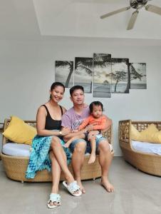 a man and woman sitting on a couch with a child at Bali Villas Panglao Bohol in Panglao Island