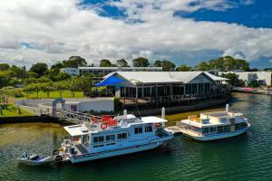 two boats docked in the water in front of a building at Caloundra Houseboats in Pelican Waters