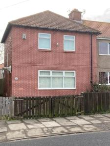 a red brick house with a wooden fence at Challoner House - sleeps 5 in Hartlepool
