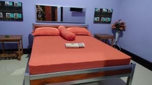 um quarto com uma cama com lençóis e almofadas laranja em Jepun Bali hotel negara em Negara