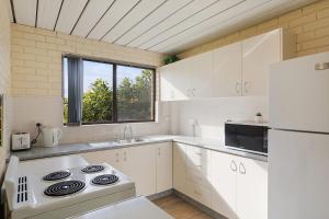 a kitchen with white cabinets and a white stove top oven at Apollo Unit 26 Ground Floor in Narooma